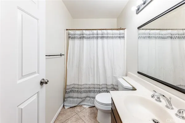 a bathroom with a sink a toilet a mirror and shower curtain