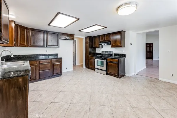 a kitchen with stainless steel appliances granite countertop a stove top oven a sink dishwasher and a refrigerator