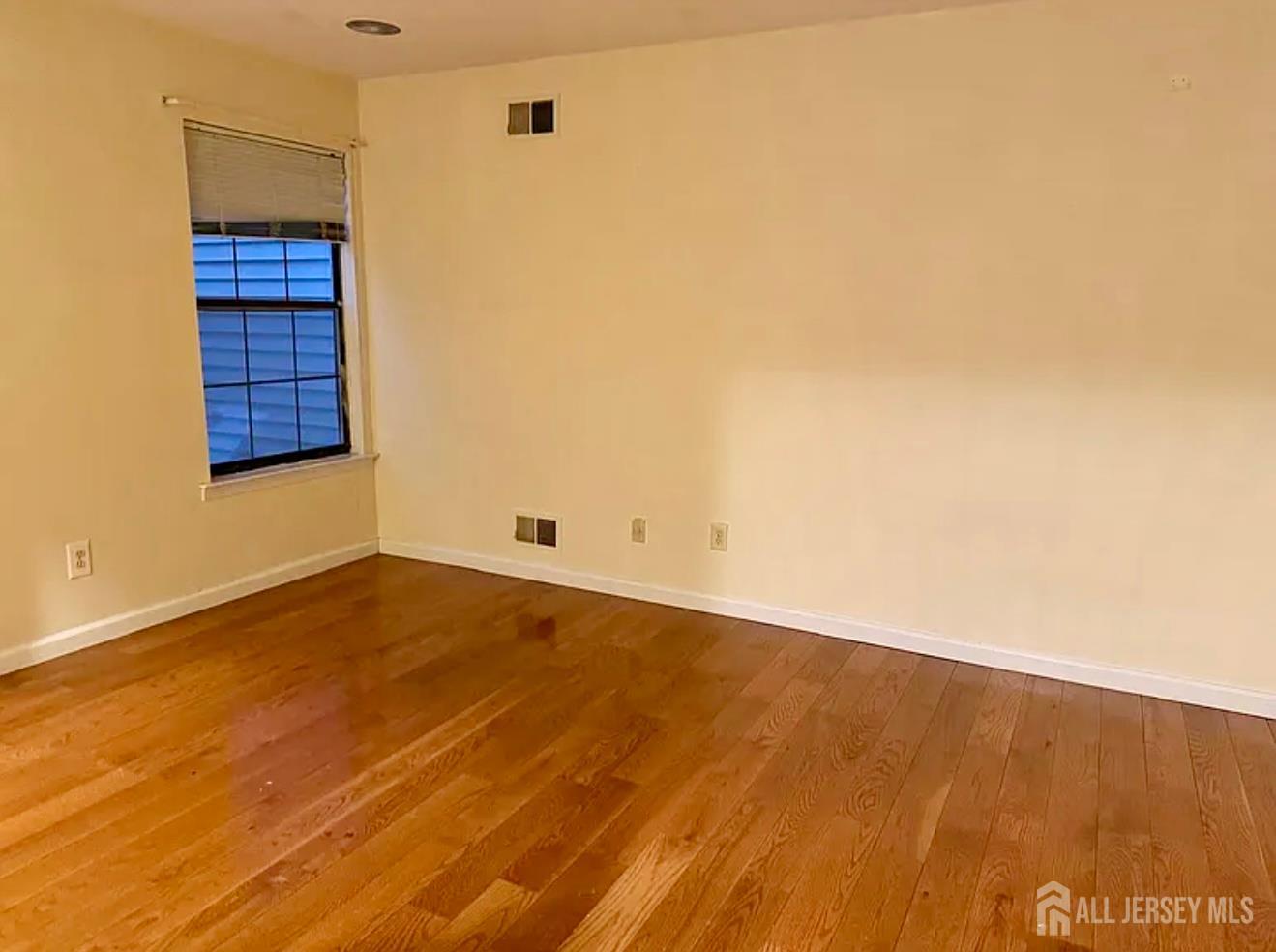 2202 Woodbridge Commons Way Iselin, NJ 08830 - Photo 6 of 6 a view of an empty room with wooden floor and a window