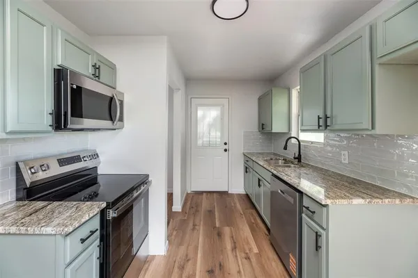 a kitchen with granite countertop a sink a stove top oven a counter space and cabinets