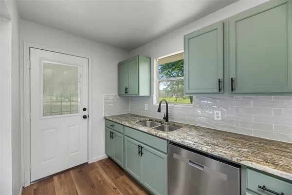 a kitchen with granite countertop a sink and a wooden floor