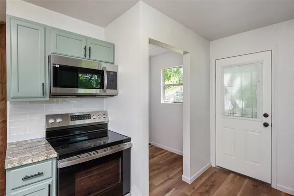a kitchen with stainless steel appliances a stove a microwave oven cabinets and a wooden floor