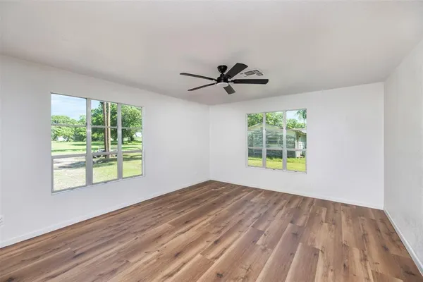 a view of an empty room with a window and wooden floor