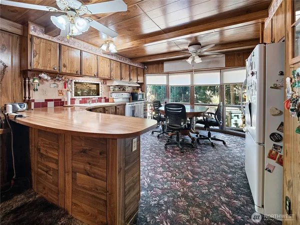 a kitchen with stainless steel appliances granite countertop a sink window and chairs
