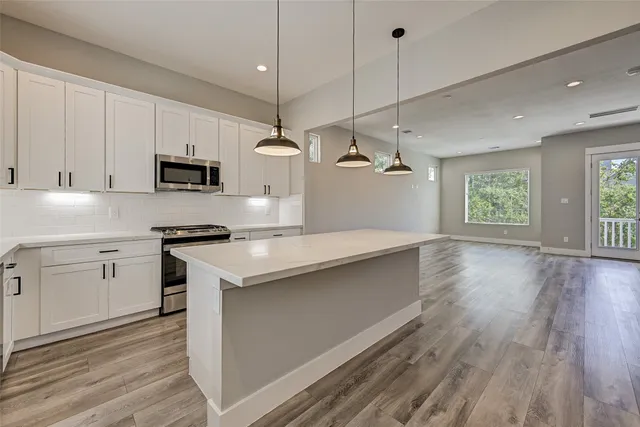 a kitchen with kitchen island granite countertop a sink a counter space appliances and cabinets