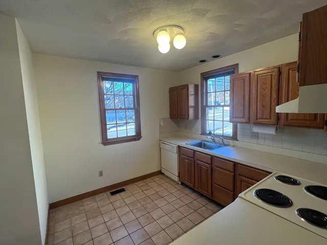 a kitchen with stainless steel appliances a sink a stove cabinets and a window