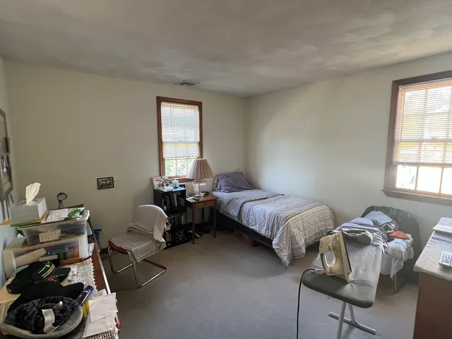 a bedroom with bed chair and window