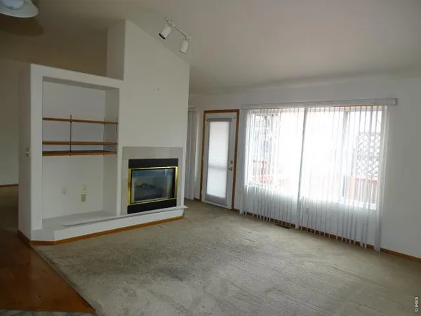 an empty room with windows and fireplace