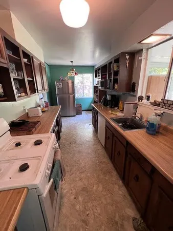 a large kitchen with sink a refrigerator and chairs