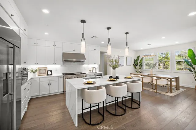 a open dining room with stainless steel appliances kitchen island granite countertop a table chairs stove a refrigerator and cabinets