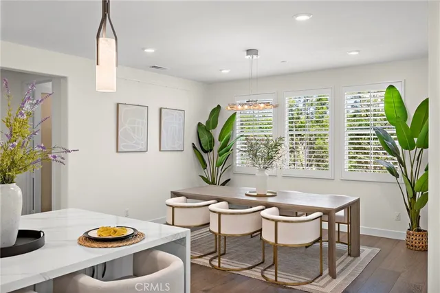 a dining room with furniture a potted plant and a large window