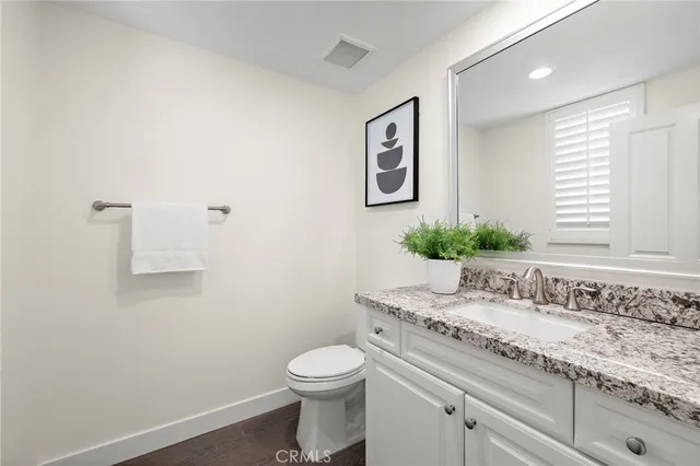a bathroom with a granite countertop sink a toilet and a large mirror