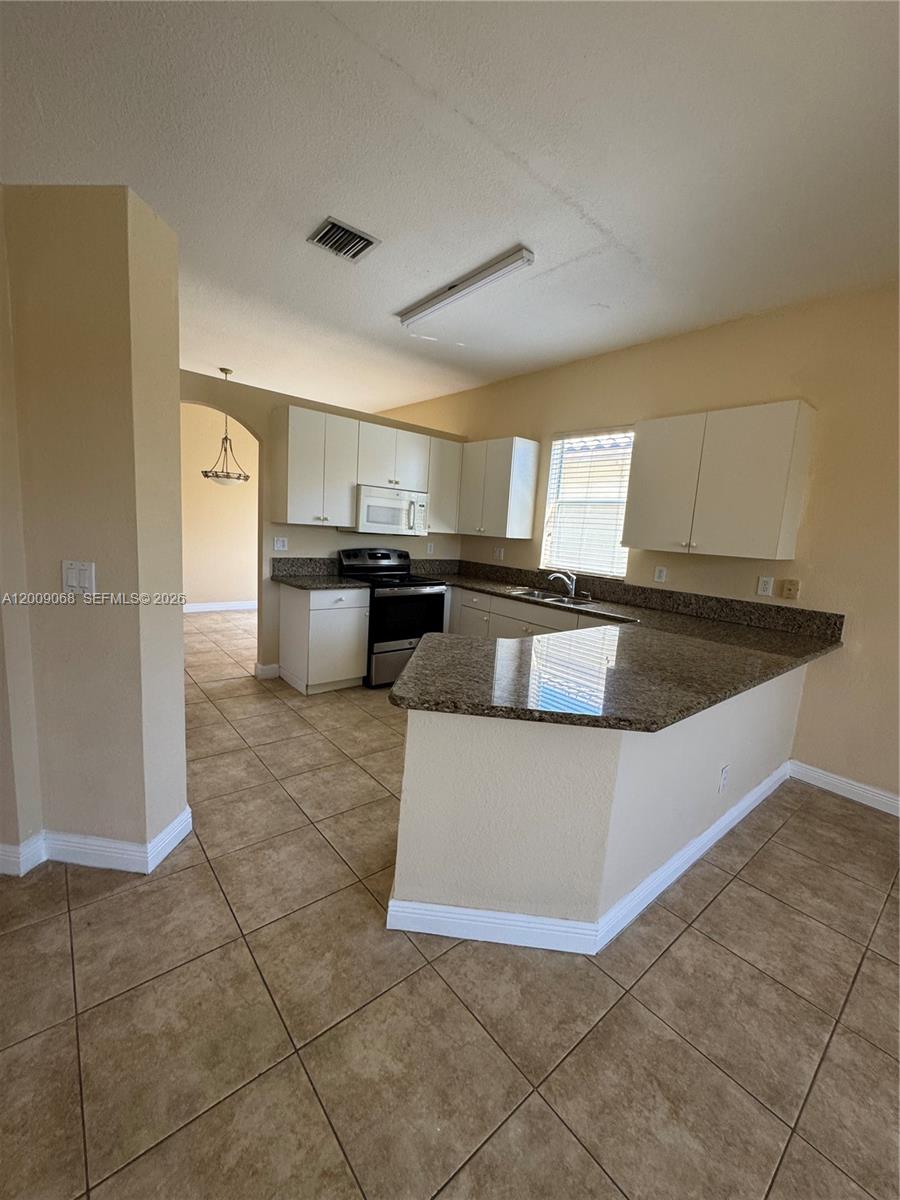 12860 Southwest 51st Street Miramar, FL 33027 - Photo 13 of 29 a large kitchen with a stove a sink dishwasher and a refrigerator