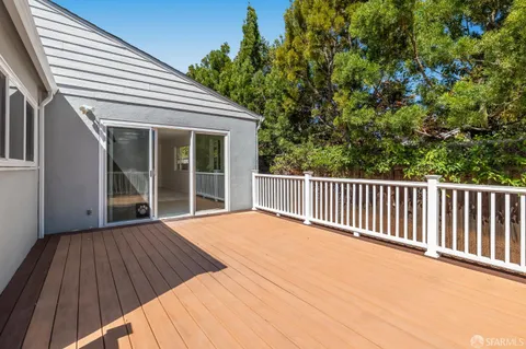 a view of backyard with large trees and wooden fence