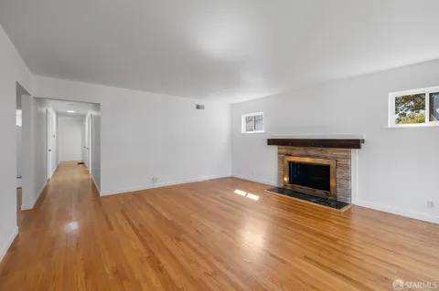 a view of empty room with wooden floor and fireplace