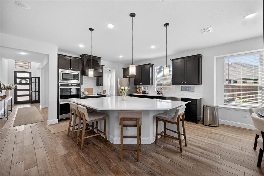 596 Randys Way Pilot Point, TX 76258 - Photo 13 of 40 a kitchen with stainless steel appliances a dining table chairs stove refrigerator and cabinets