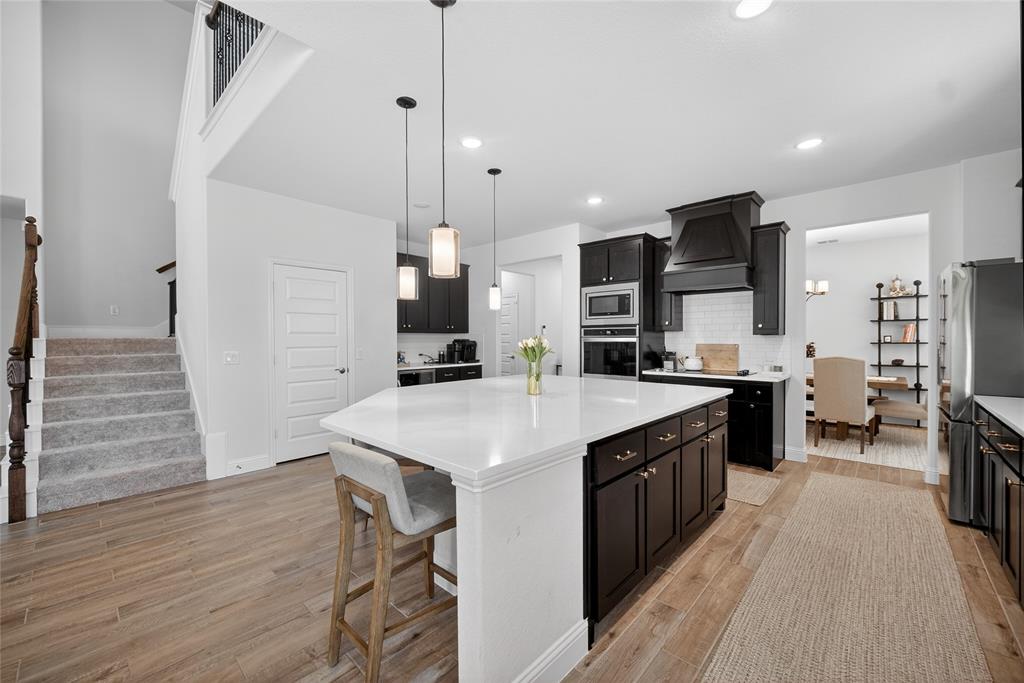 596 Randys Way Pilot Point, TX 76258 - Photo 14 of 40 a large kitchen with stainless steel appliances kitchen island granite countertop a table chairs sink and cabinets