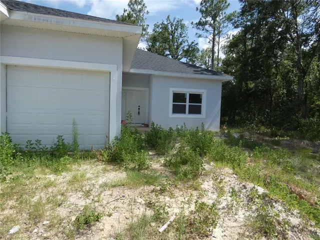 a backyard of a house with plants and large tree