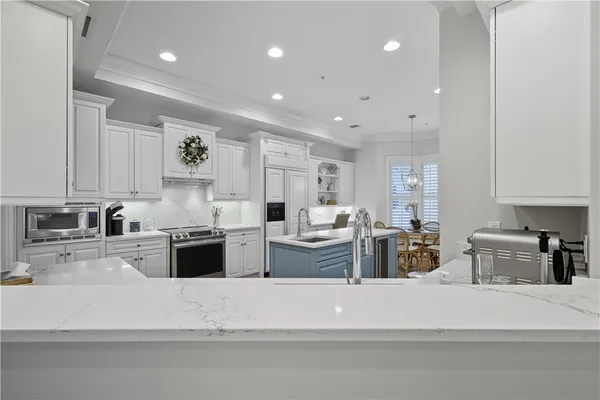 a kitchen with stainless steel appliances kitchen island granite countertop a stove a sink a refrigerator and white cabinets
