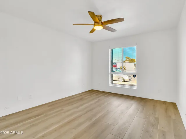 an empty room with wooden floor ceiling fan and windows