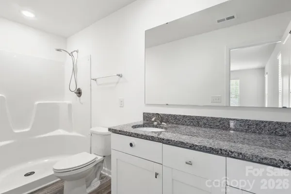 a bathroom with a granite countertop sink a toilet and a shower