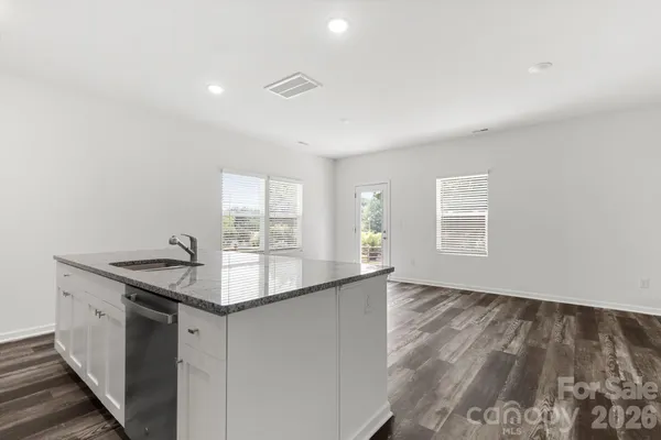 a kitchen with granite countertop a sink and dishwasher with wooden floor