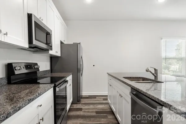 a kitchen with stainless steel appliances granite countertop a sink stove and refrigerator