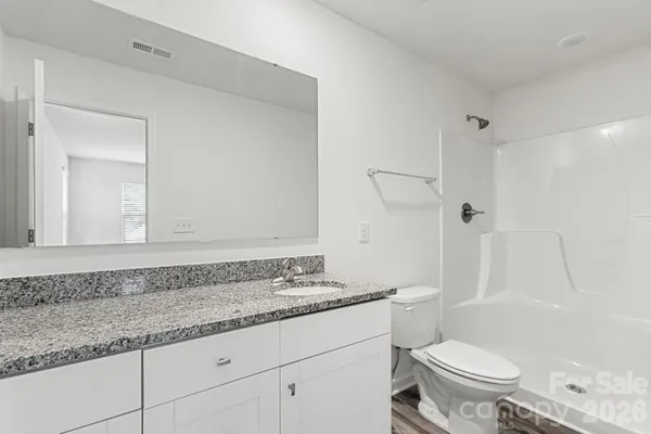 a bathroom with a granite countertop sink a toilet and a shower