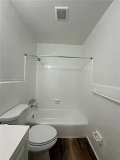 a bathroom with a granite countertop toilet and a bathtub