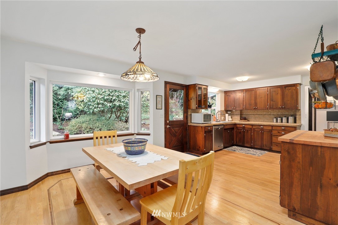 9302 Northeast 180th Street Bothell, WA 98011 - Photo 8 of 40 a open kitchen with stainless steel appliances kitchen island granite countertop a refrigerator a sink dishwasher a dining table and chairs with wooden floor