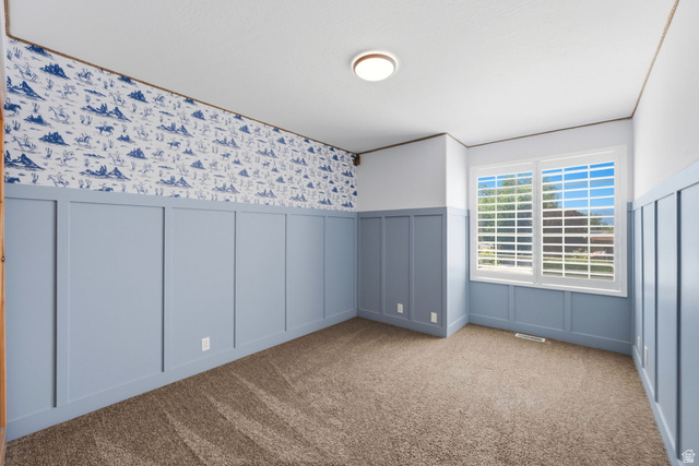 3732 Campbell Road Tooele, UT 84074 - Photo 38 of 69 Carpeted room featuring light blue board and batten paneling, decorative wallpaper, a dual-pane window with white plantation shutters, and a flush-mount ceiling light fixture