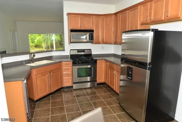 a kitchen with a sink a stove a microwave cabinets and a window