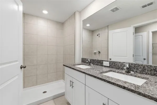 a bathroom with a granite countertop sink mirror and shower