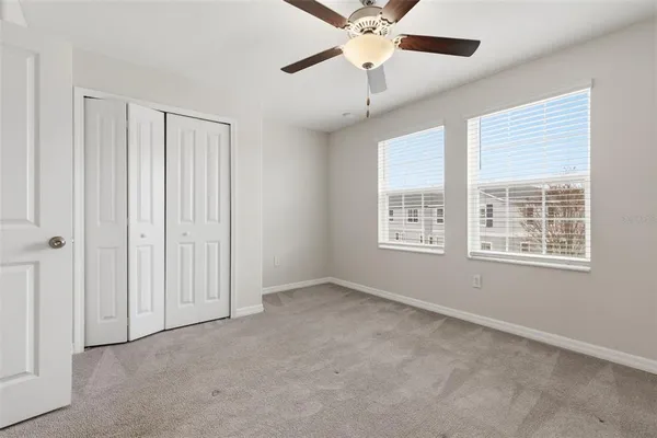 an empty room with chandelier fan and windows