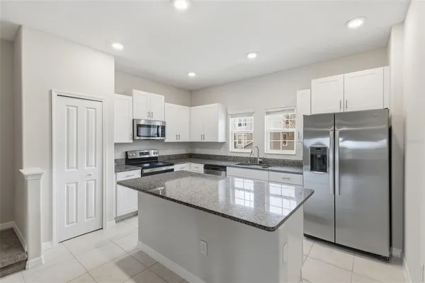 a kitchen with stainless steel appliances granite countertop a refrigerator a sink and a stove