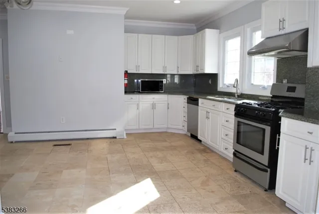 a kitchen with stainless steel appliances granite countertop a stove a sink and a white cabinets