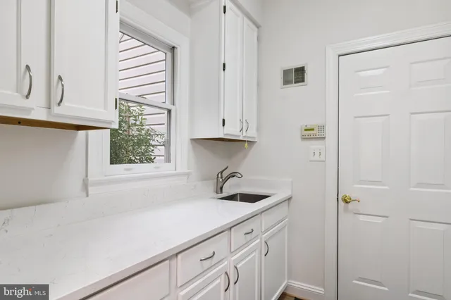 a kitchen with white cabinets and window
