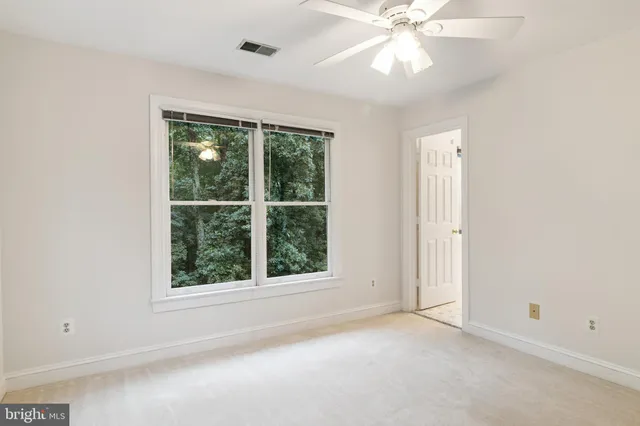 an empty room with a window and a fan