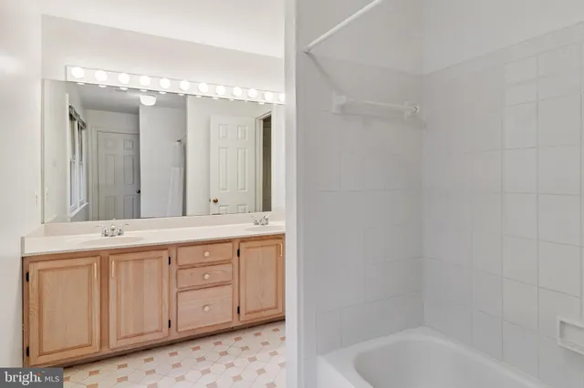 a bathroom with a double vanity sink mirror and bathtub
