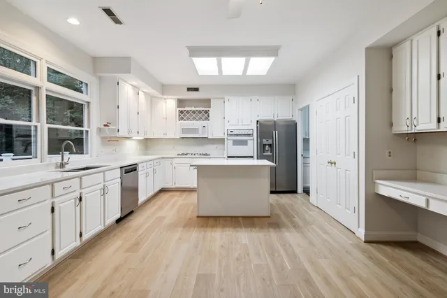 a large kitchen with stainless steel appliances sink refrigerator and window