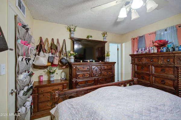a bedroom with a bed and a flat tv screen on dresser
