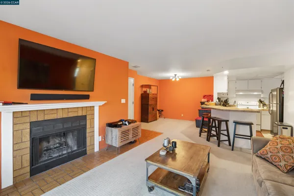 a living room with furniture a fireplace and kitchen view