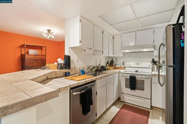 a kitchen with stainless steel appliances granite countertop a sink a stove a refrigerator and white cabinets