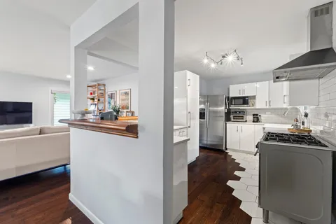 a kitchen view with stainless steel appliances a refrigerator a stove a sink dishwasher a oven with white cabinets and wooden floor