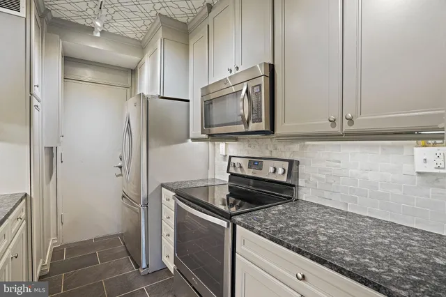 a kitchen with stainless steel appliances granite countertop a refrigerator and a stove