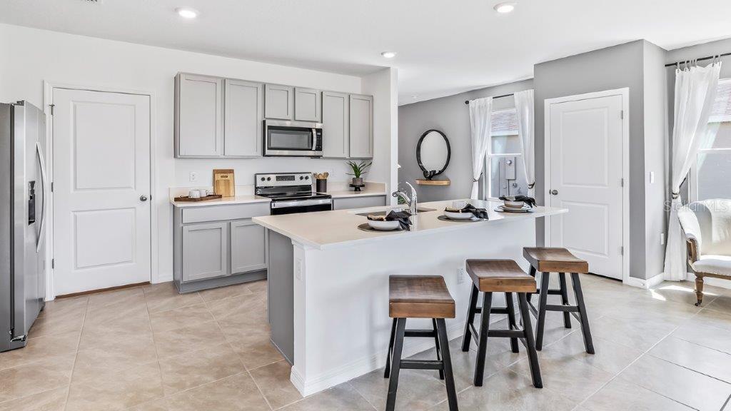 17811 Acorn Drop Road Land O Lakes, FL 34638 - Photo 2 of 11 a kitchen with stainless steel appliances granite countertop a stove a sink a dining table and chairs