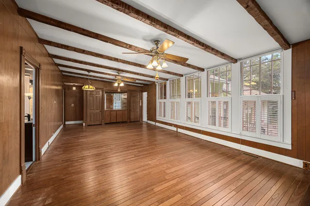 en empty room with wooden floor and windows