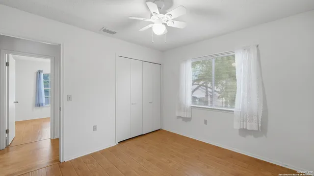 a view of an empty room with window and wooden floor
