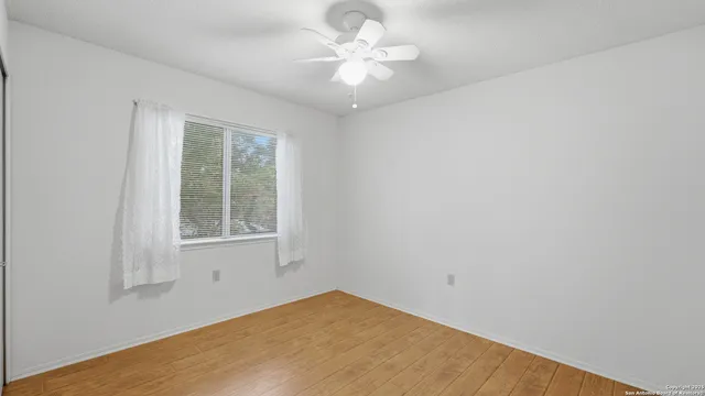 an empty room with a window and a fan