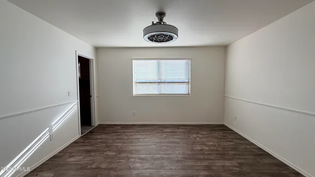 an empty room with a window and a ceiling fan